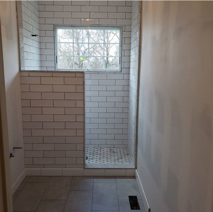 subway tile shower with marble floor